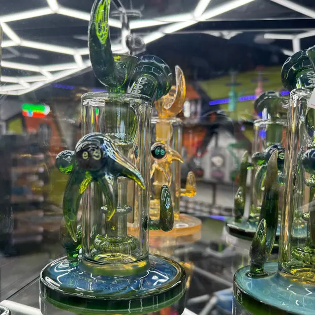 Green and amber glass recyclers lit by the honeycomb LED ceiling at Kief Smoke Shop