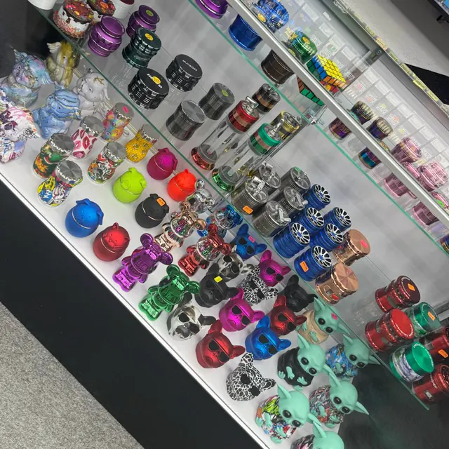 Rows of coloured metal grinders in the lit display case