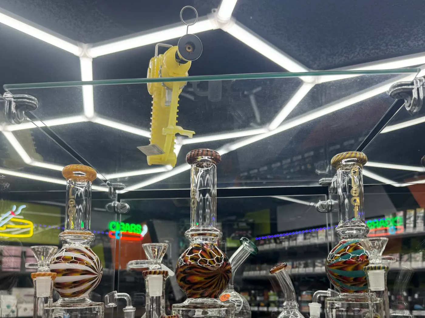 Glass rigs on lit shelves under the honeycomb LED ceiling at Kief Smoke Shop